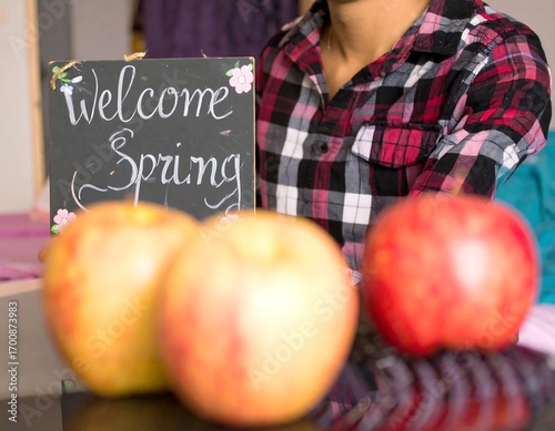 Person holding a welcome spring sign with apples
