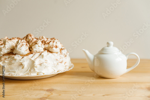 Homemade cake decorated with cream and a white teapot (in a blur).