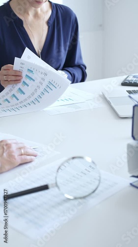 Group of auditors analyzing financial reports with magnifying glass and documents close up, performing accounting and auditing tasks in the office. Audit and taxes in business