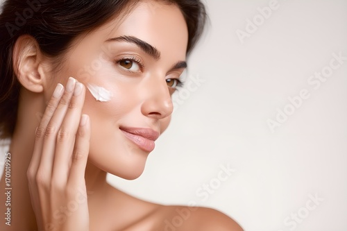 Woman applying face cream as part of daily skincare routine for hydration and beauty treatment with focus on healthy skin. Hands applying moisturizing cream on face. Anti-aging skin care