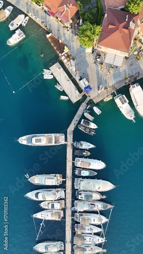 Aerial view of yachts and boats parked at a marina with turquoise sea background