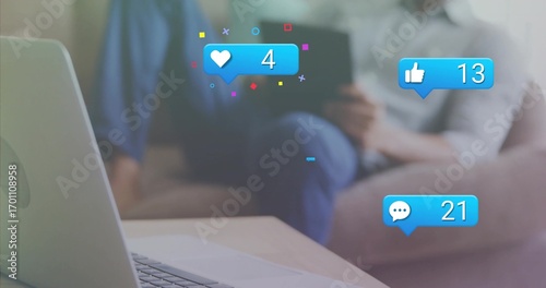 Man holding tablet on sofa in living room, laptop on coffee table, social-media-icons, copy space