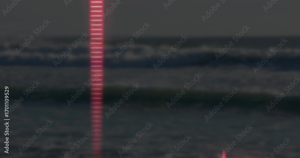 Fototapeta Shining narrow vertical red beam reflecting off ocean waves at seaside at night, faint horizon line