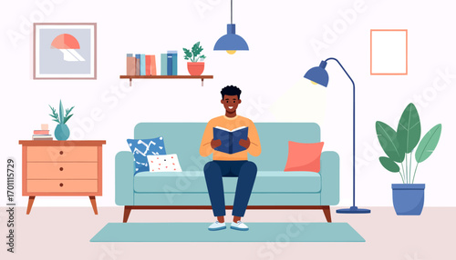 Cozy home lifestyle concept with a happy African man engrossed in reading a book while sitting comfortably on the living room sofa