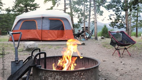Warm fire lights comes from soft burning camp fire in metal fire ring at camp site, in nature
