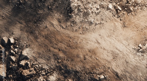 High-angle view of a rugged, uneven landscape of dirt and rocks.  Streaks of varying colors of brown and beige dirt flow across the image
