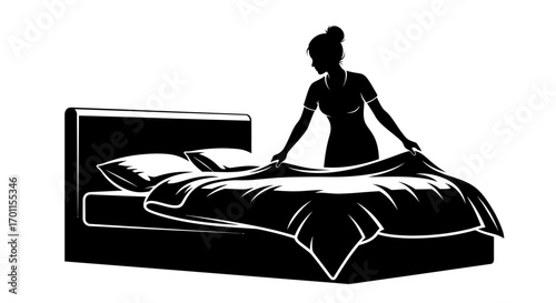 Silhouette of a woman making a bed with pillows and a blanket.