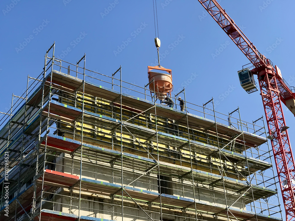 Naklejka premium A massive structure being built with scaffolding and a crane. Constructing building of a skyscraper in the urban landscape