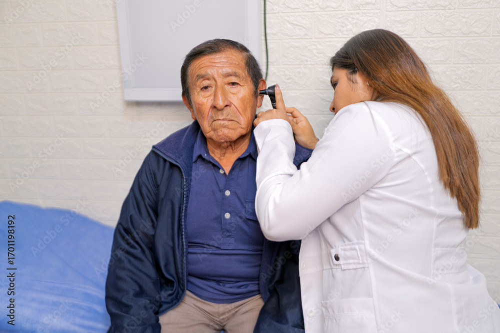 Fototapeta premium Doctor examining senior man's ear with otoscope in clinic