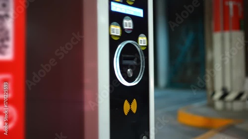Close up of a hand inserting a parking ticket into the exit machine to lift the barrier gate. Transportation, parking system, payment process, urban service, automation, and modern city convenience