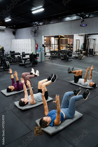 Group of latin fitness enthusiasts practicing workout on mats, enhancing flexibility and strength in contemporary gym setting