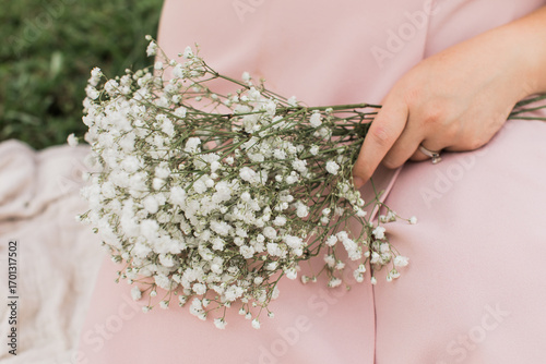 a woman holding a bouquet of white baby breathe flowers in her hand closeup in a blush pink dress