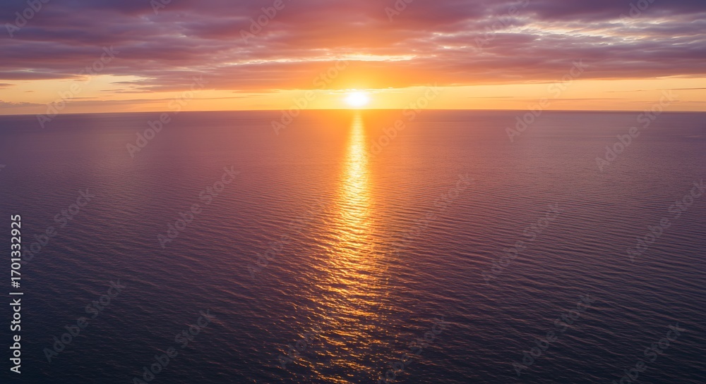 Obraz premium Sunset over calm water creating a vibrant orange and purple sky