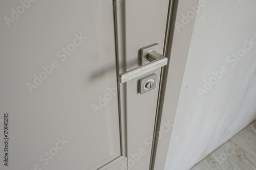 A close-up of a closed, gray door with a modern, rectangular silver handle and lock