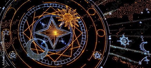 Wallpaper Mural a night sky-themed light installation. The central design features glowing yellow and white lines, a star, sun, and crescent moon, with intricate geometric patterns. Surrounding the celestial symbols Torontodigital.ca