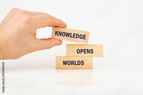 Academic education learning concept. Words KNOWLEDGE OPENS WORLDS made from blocks with hand on white background