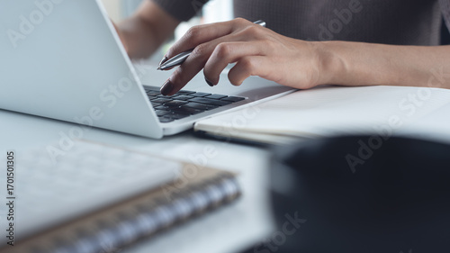 Close up of business woman working on laptop, searching the information and writing on notebook, business planning. Student studying online class via laptop, e-learning, online research