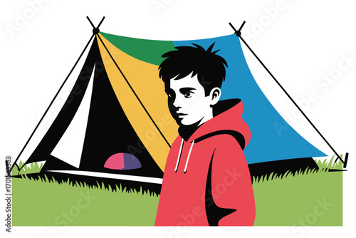 Young boy standing in front of colorful camping tent in a green field