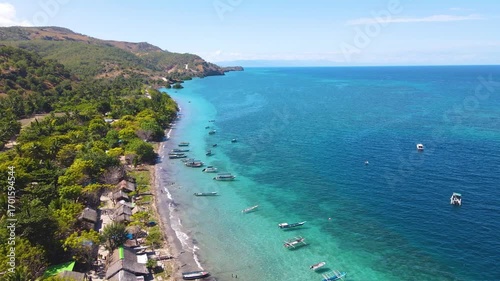 Stunning aerial view of the Atauro Island coastline in Timor-Leste. Traditional outrigger boats are moored in the clear turquoise water along an authentic fishing village.