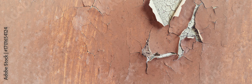 Peeling paint on the wall. Panorama of a concrete wall with old cracked flaking paint. Weathered rough painted surface with patterns of cracks and peeling. Wide panoramic texture for design background