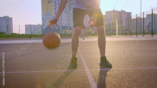 Training with a basketball on an outdoor sports court, man practising with the ball, camera tracking