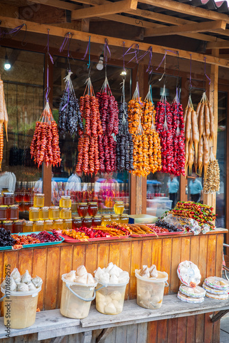 A vibrant display of churchkhela, dried fruits, honey jars, and local sweets at a Georgian market stall. This traditional snack scene highlights the rich food culture and authentic flavors of Georgia