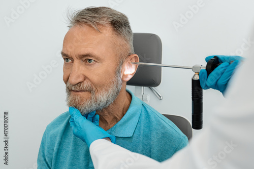 Tableau sur toile ENT doctor examining elderly man's ear using video endoscope at otolaryngology clinic