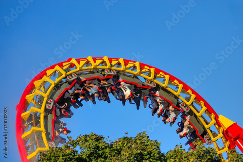 Riders experience an exhilarating upside-down inversion on a vibrant red and yellow roller coaster
