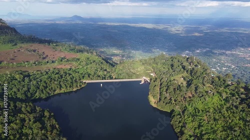 Wallpaper Mural Aerial view of a serene lake surrounded by lush green forest and distant mountains under a cloudy sky Torontodigital.ca
