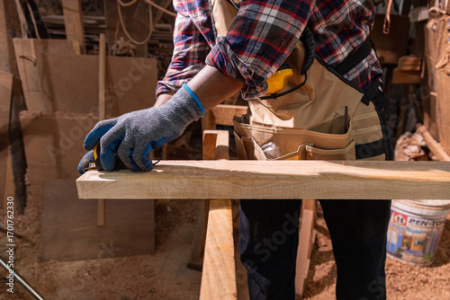 Focused carpenter measuring wood with tape