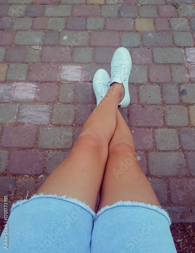 Person with a casual mood relaxing with their feet crossed on a stone pavement