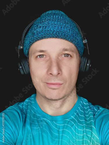 a man in a hat and headphones. A selfie portrait on a smartphone