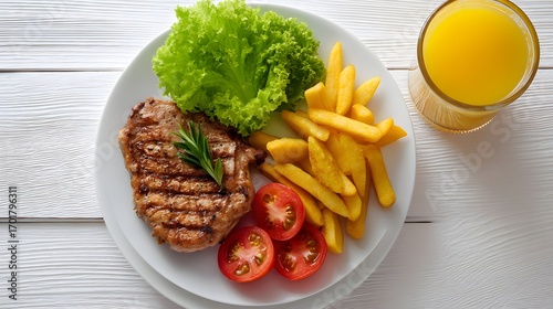 A delicious plate featuring grilled steak, fresh lettuce, tomatoes, crispy fries, and a glass of orange juice, perfect for a hearty meal.