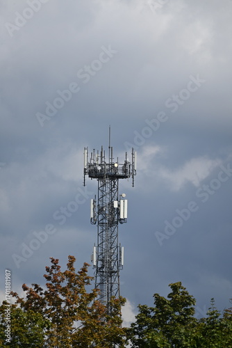 Lattice mast with 5G antennas between houses, light clouds in the sky
