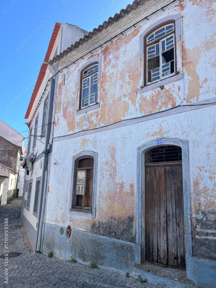 Fototapeta premium Vieil immeuble coloré abandonné à Faro, Algarve, Portugal – architecture urbaine pittoresque et atmosphère nostalgique