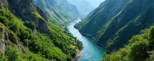 A wide turquoise river flows through a lush green valley with steep tree covered mountains