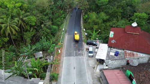 Aerial view of asphalt road repair with trial compaction process, testing surface quality before final paving. Infrastructure construction footage