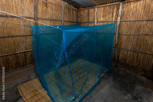 Reed-Walled African House with Blue Mosquito Net over Traditional Reed Mat