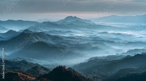 Majestic layers of a blue mountain range fading into the horizon through a serene sea of clouds and mist at dawn
