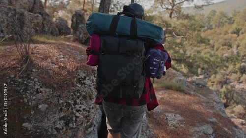 A man with a large backpack and hiking equipment in the mountains.