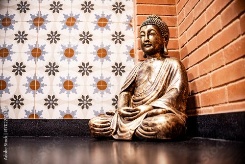 Golden Buddha Statue in Meditation Pose Against Decorative Wall