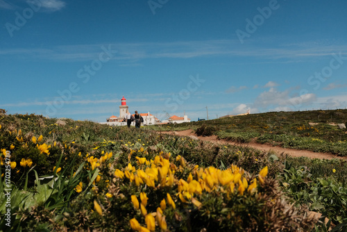 Lush green hills and rugged terrain with blue sky and scattered clouds in Cabo da Roca Sintra Portugal natural landscape with vegetation from scenic hiking trail