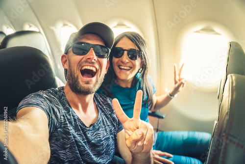 Smiling couple taking selfie inside airplane during flight, showing joy, freedom and travel lifestyle concept