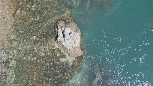 4k Aerial top down still drone video of the blue Neretva River near Mostar Old Bridge, showing rocks emerging from the water and ducks swimming peacefully in the scenic river landscape.
