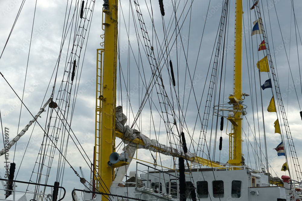 Obraz premium ship masts and flags against a cloudy sky