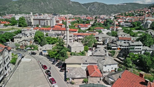 4k Drone video in tracking movement around Nezir Agina Mosque in Mostar, Bosnia and Herzegovina, with Hajji Kurt Mosque and the abandoned Mostar Marriott Hotel visible in the background during the day