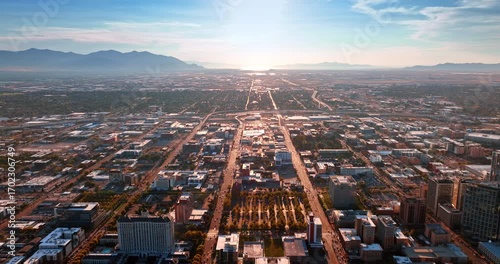 Straight parallel roads cross the urban landscape of the large city. Mountain silhouettes surround the territory of Salt Lake City, Utah, USA. Aerial view.