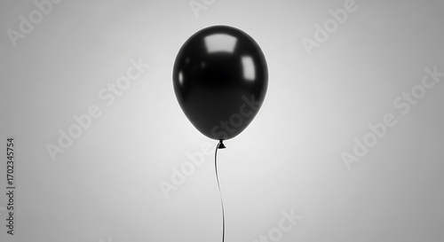 A glossy black balloon floats against a plain gray backdrop.