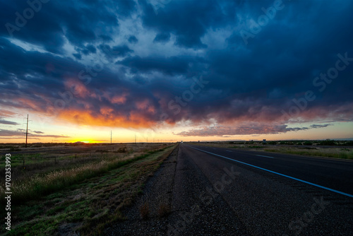 Photography Vibrant sunset over an open highway in a rural Texas with dramatic clouds on a w