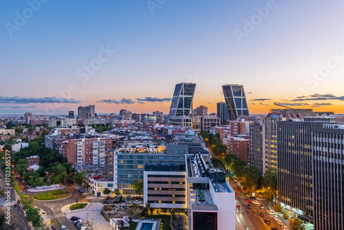Aerial view of Madrid at dusk, looking from north to south, with the city bathed in warm twilight tones. 